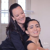 Fernanda Bianchini posicionando a bailarina numa pose quanto ambas sorriem.